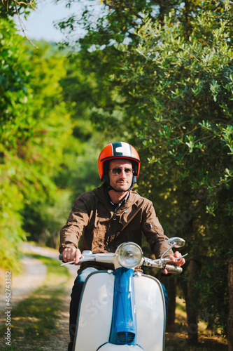 Portrait of man riding vintage motor scooter, Tuscany, Italy photo