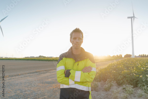 Portrait of engineer standing on field path at a wind farm photo