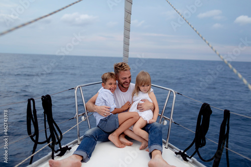 Father with his children sitting on boat deck during sailing trip