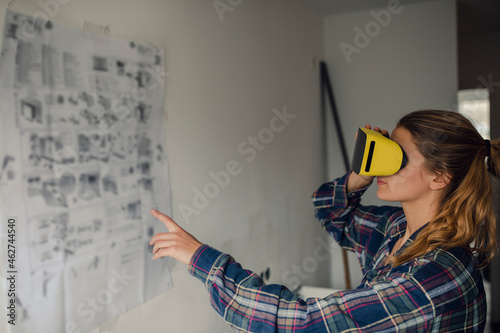 Young woman wearing VR glasses with assembly instructions at the wall photo