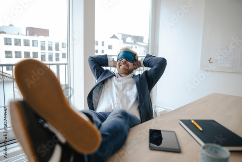 Businessman having a power nap at desk in office photo