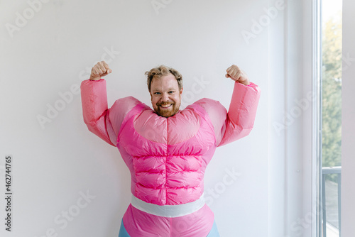 Proud man wearing pink bodybuilder costume flexing his muscles