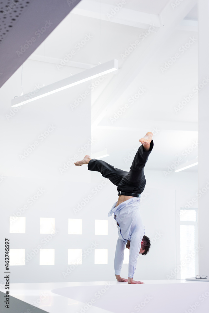 Businessman doing a handstand on reception desk in office Businessman doing a handstand on reception desk in office