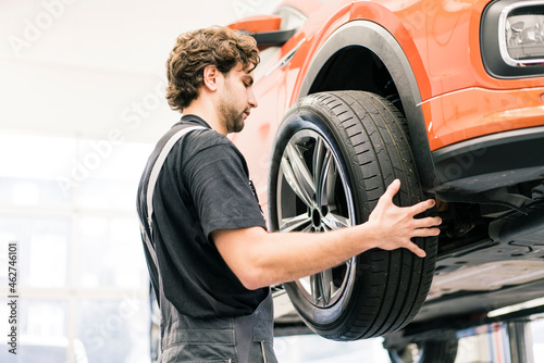 Car mechanic in a workshop changing tire photo