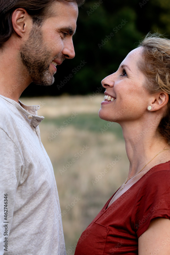 Happy couple in nature, standing face to face, smiling at each other Happy couple in nature, standing face to face, smiling at each other
