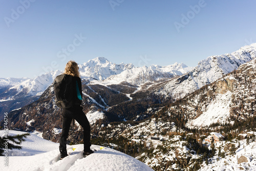 Woman stanging with snowshoes on viewpoint, Valmalenco, Italy photo