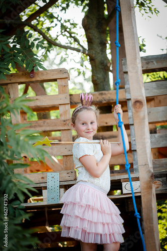 Girl dressed as a princess with crown and sceptre playing in a tree house photo