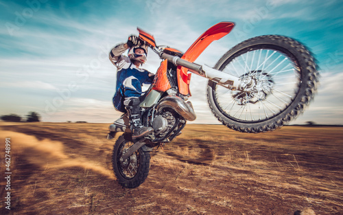 Motocross driver performing wheelie photo