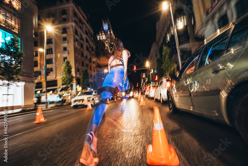 Woman running in Madrid city with flashing lights at night