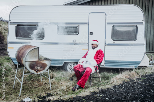 Iceland, Santa Claus sitting in front of caravan barbecueing photo