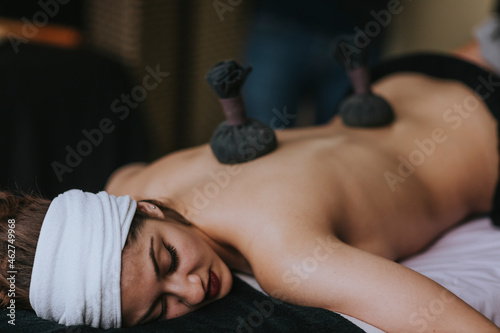 Young woman with sachets on her back during stamp massage photo