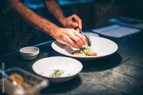 Cook serving food on a plate in the kitchen of a restaurant photo