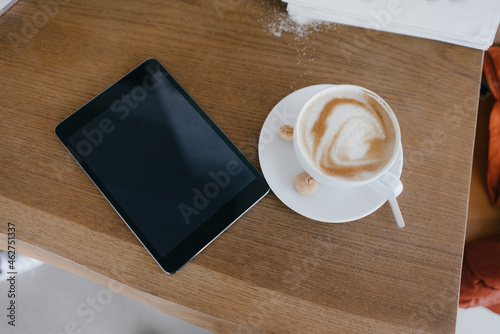 Digital tablet on desk with cup of cappuccino with photo