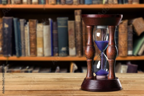 Antique hourglass and collection of old books, history and knowledge concept