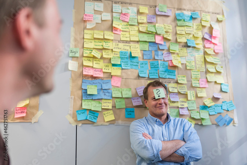 Businessman with sticky note sticking at his forehead in office photo
