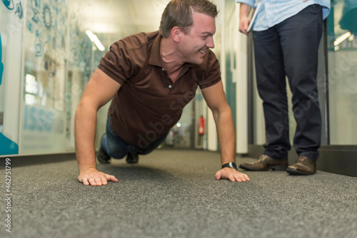 Businessman doing push-ups on office floor photo