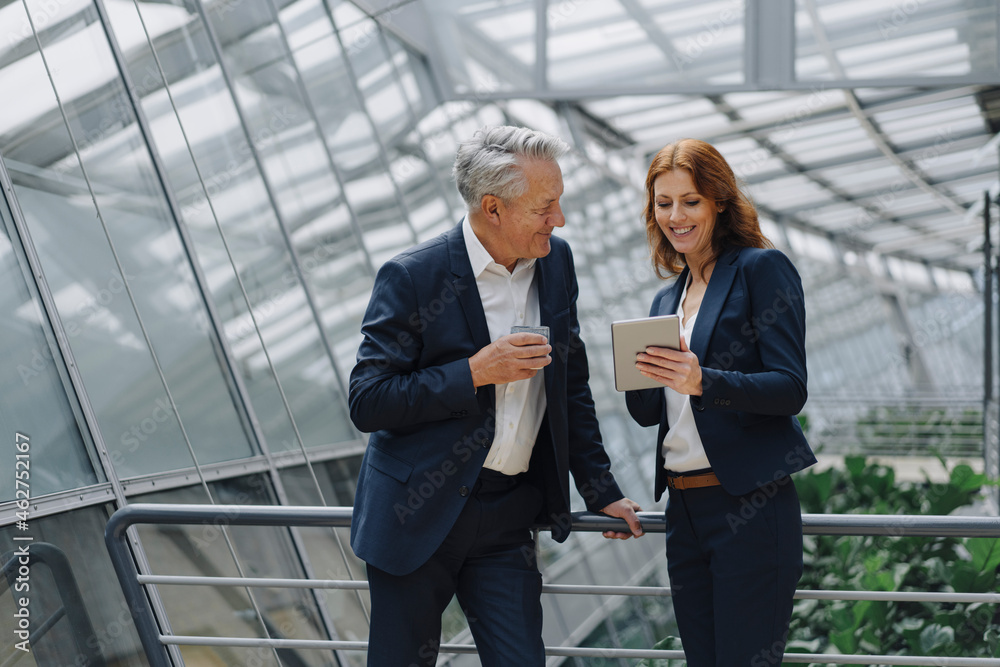 Smiling businessman and businesswoman talking in modern office building Smiling businessman and businesswoman talking in modern office building