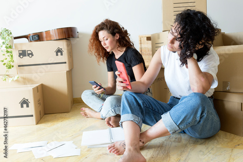 Two friends moving into new home using cell phones photo