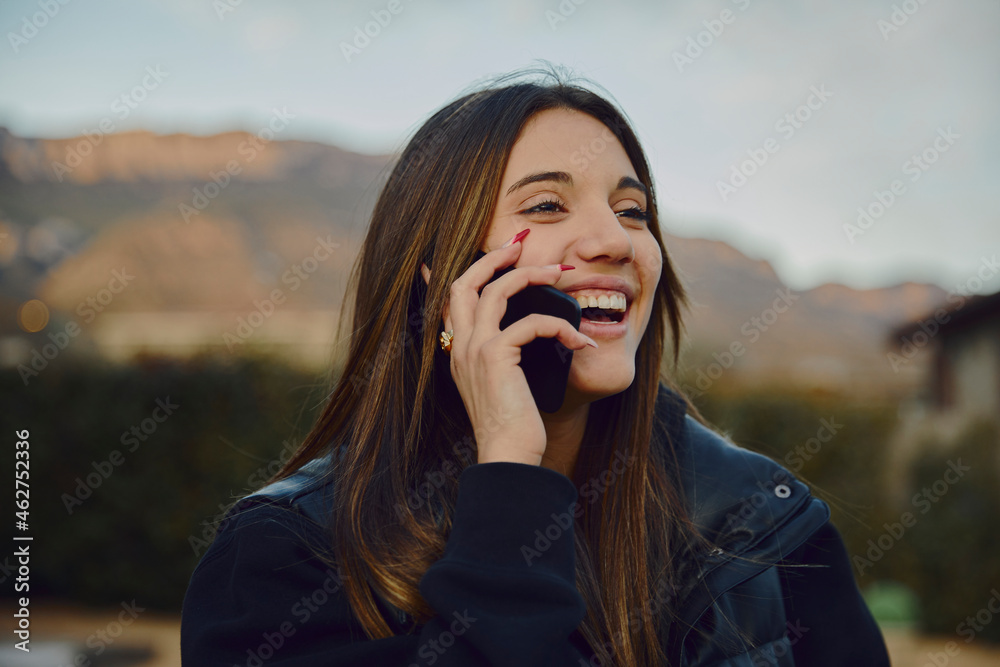 Laughing beautiful woman talking on smart phone with mountains in background Laughing beautiful woman talking on smart phone with mountains in background