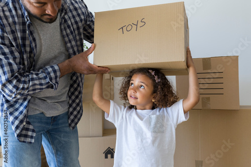 Father with daughter carrying cardboard box at new home