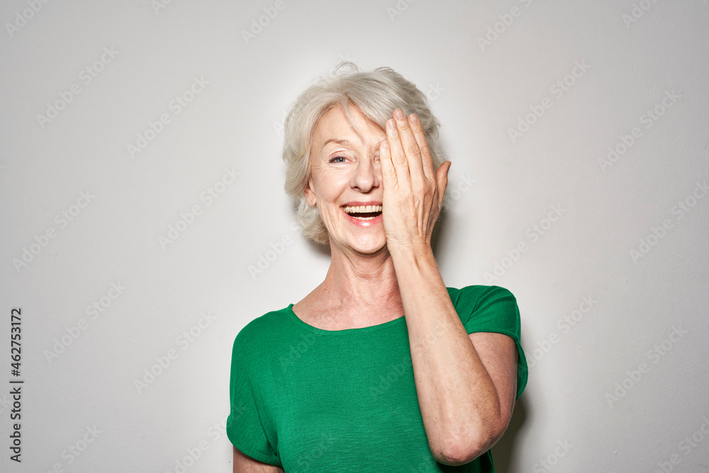 Portrait of laughing mature woman covering eye with her hand Portrait of laughing mature woman covering eye with her hand
