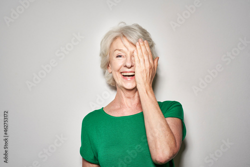 Portrait of laughing mature woman covering eye with her hand