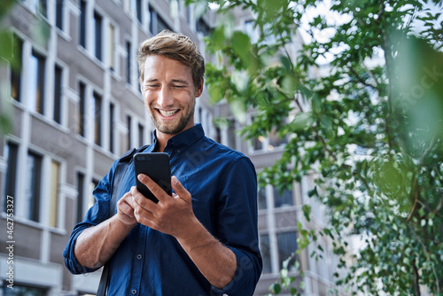 Happy young businessman using mobile phone in the city photo