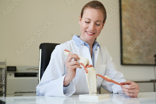 Female doctor with knee joint model in medical practice photo