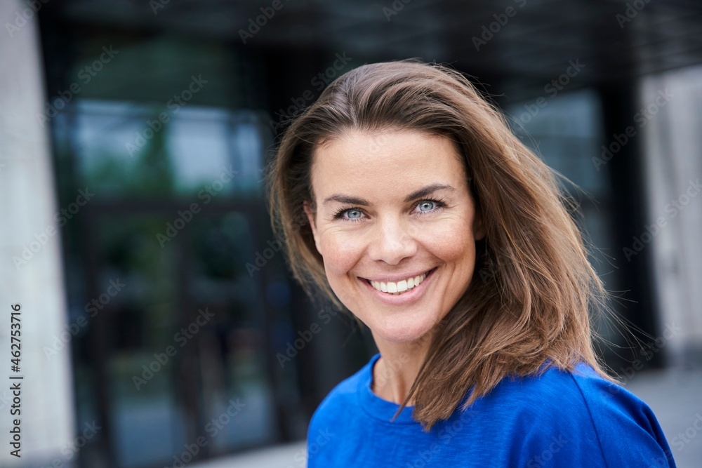 Portrait of attractive brunette woman wearing blue top in the city