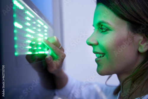 Close-up of smiling woman touching green led touchscreen photo