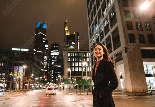 Young woman crossing the street in the city at night, Frankfurt, Germany photo