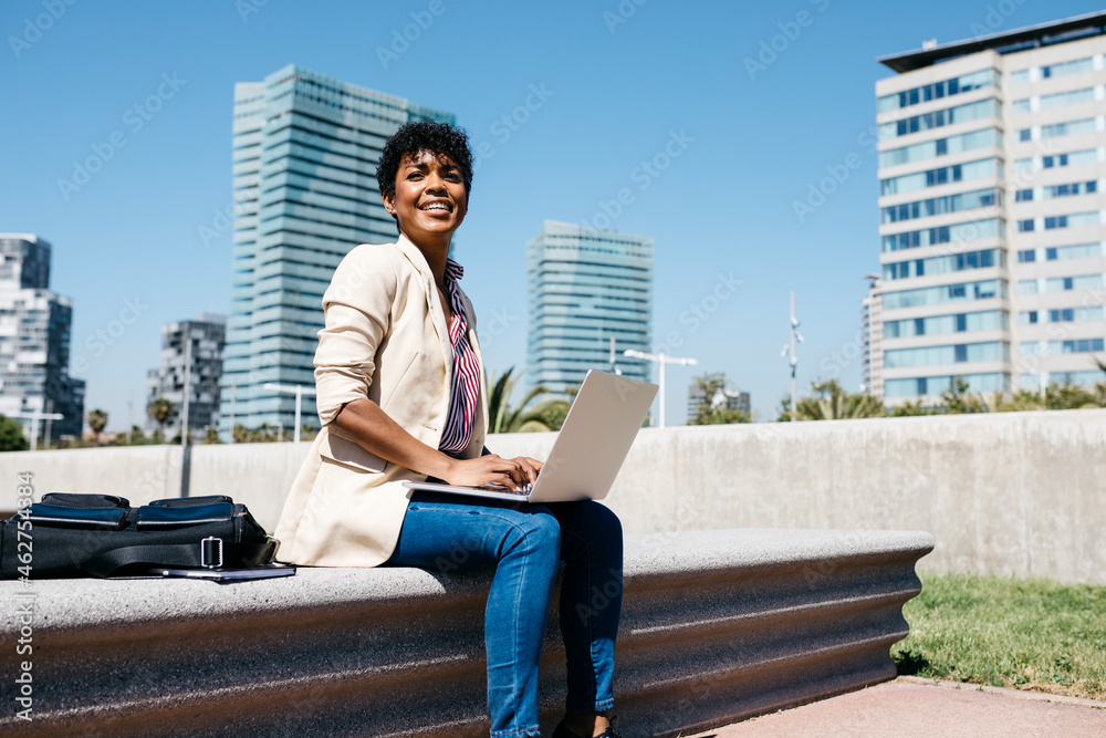 Businesswoman sitting on bench and using laptop in the city Businesswoman sitting on bench and using laptop in the city