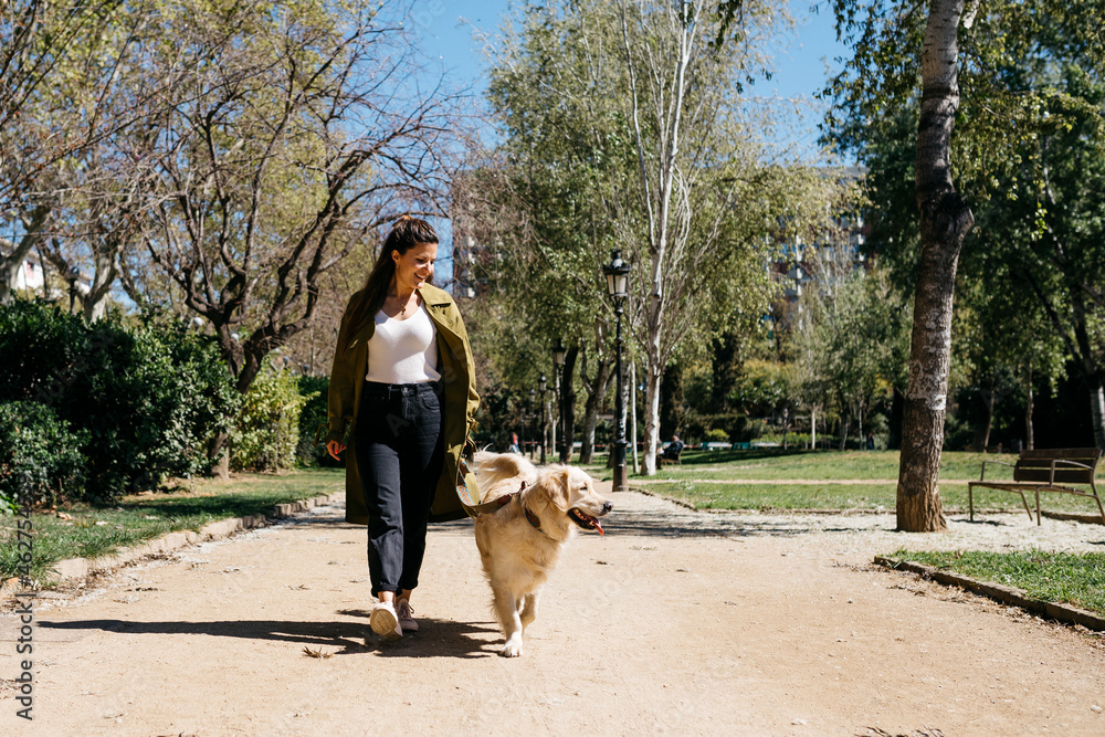 Happy woman going walkies in city park with her Labrador Retriever Happy woman going walkies in city park with her Labrador Retriever