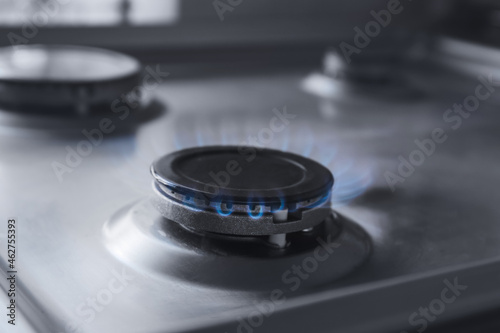 Gas burner with blue flame on domestic stove, closeup