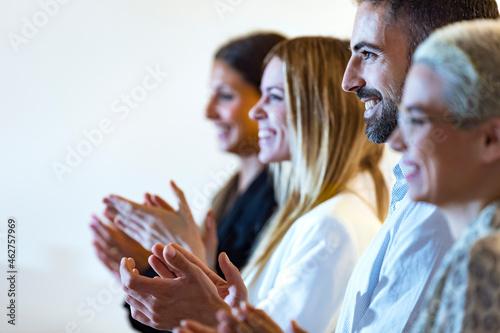 Happy business people clapping hands in office