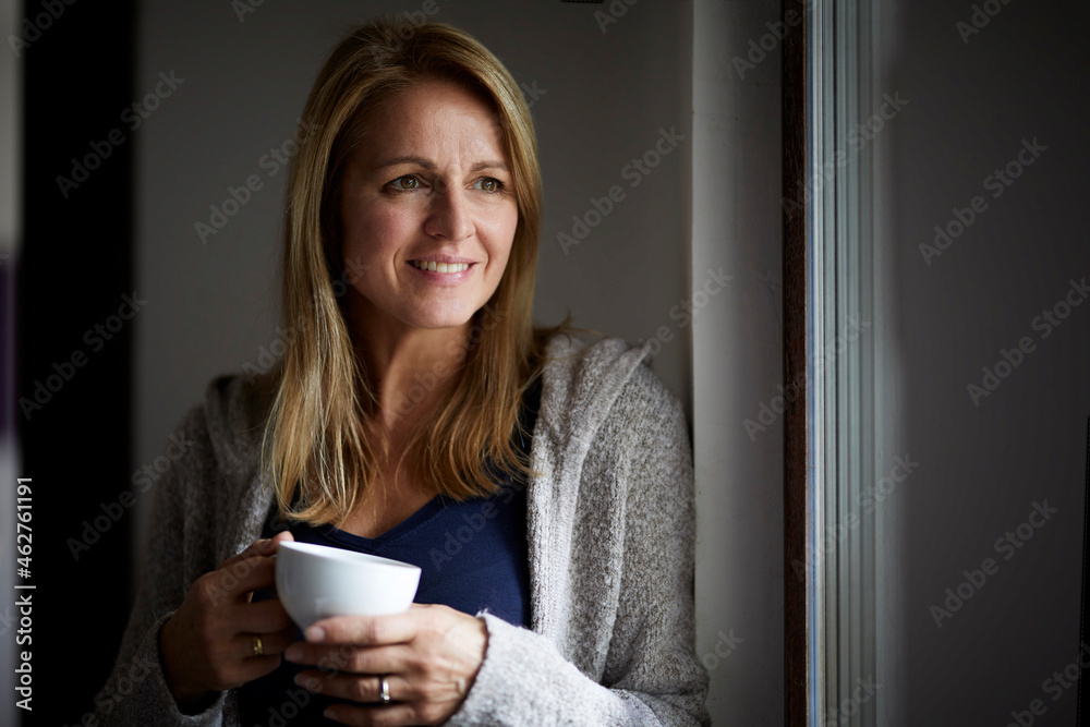 Smiling woman drinking coffee, looking out of window Smiling woman drinking coffee, looking out of window