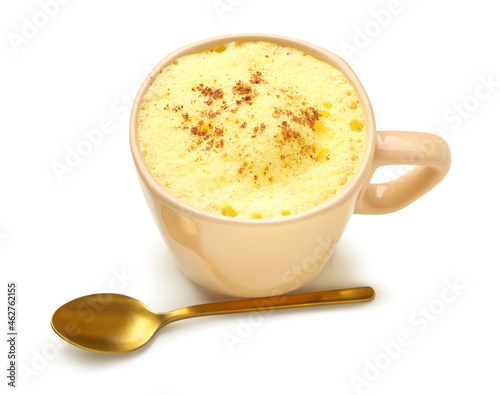 Cup of tasty turmeric latte with spoon on white background