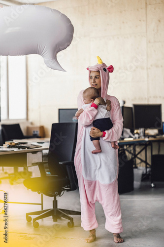 Young mother in unicorn onesie, holding her son in her arms, with speech bubble over her head