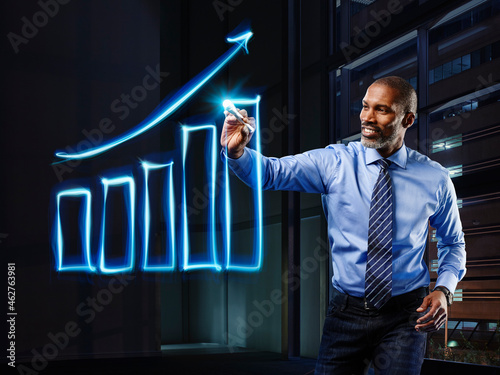 Businessman painting upturning bar chart with light