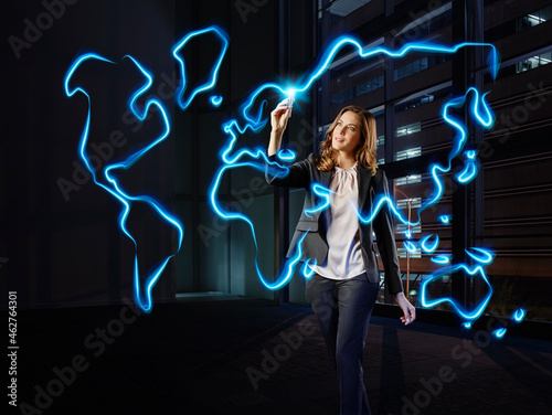 Businesswoman painting a worldmap with light, pointing on Europe photo