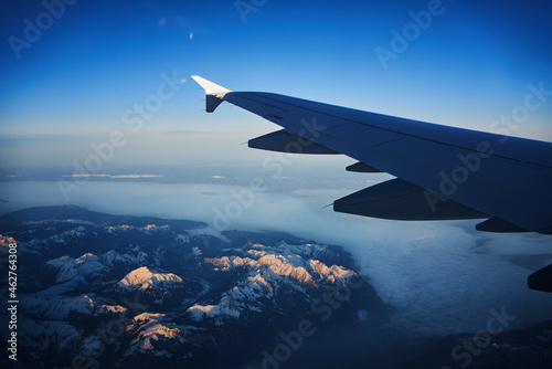 France, Auvergne-Rhone-Alpes, Wing of Airbus A321 flying over European Alps and Lake Geneva at dawn