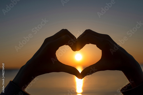 Germany, Mecklenburg-West Pomerania, Poel Island, Silhouette of hands making heart shape by sea at sunset