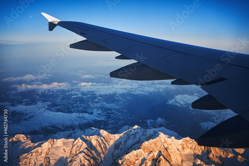 France, Auvergne-Rhone-Alpes, Wing of Airbus A321 flying over European Alps and Lake Geneva at dawn photo