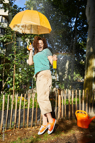 Young laughing woman with umbrella and limonade in garden photo