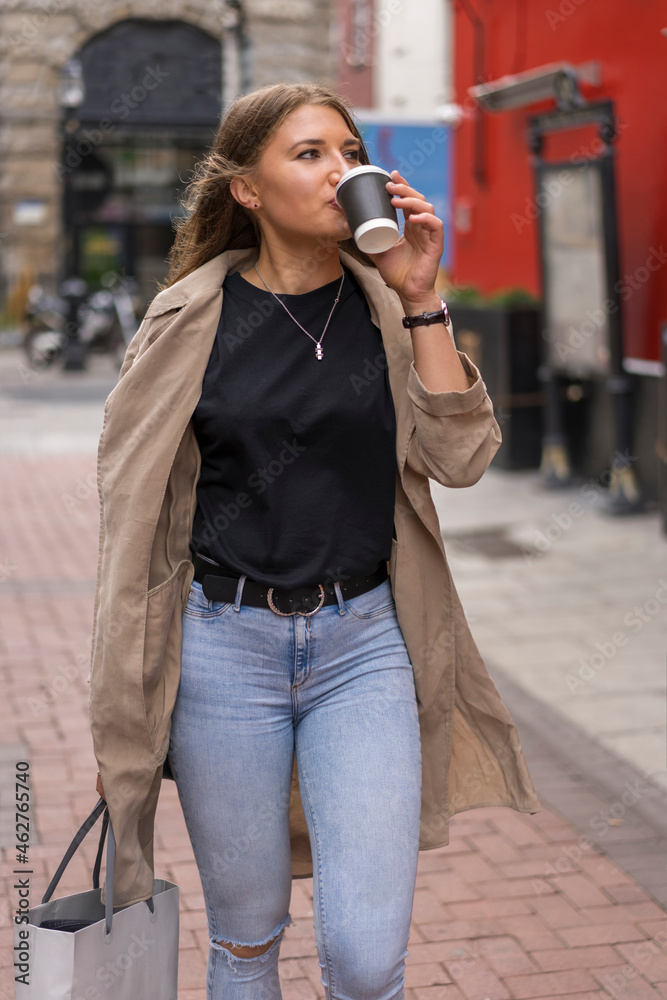 Young woman drinking coffee while looking away walking on street Young woman drinking coffee while looking away walking on street