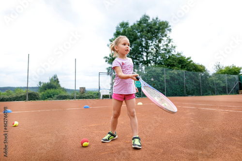 Little girl, lerning to play tennis photo