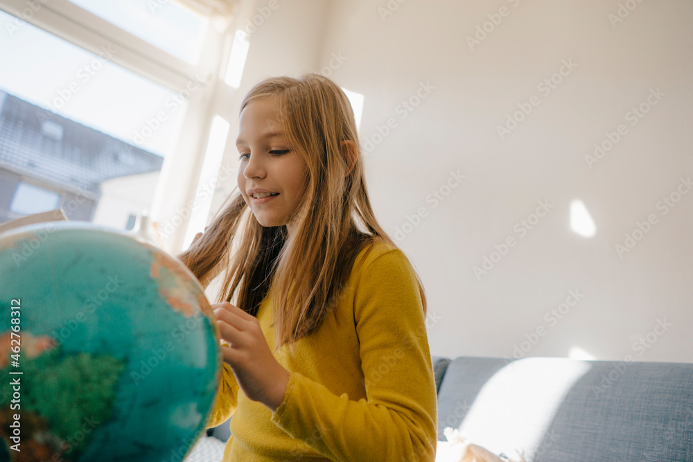 Girl at home looking at globe Girl at home looking at globe