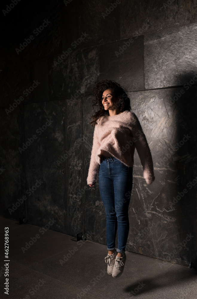 Cheerful woman jumping against wall Cheerful woman jumping against wall