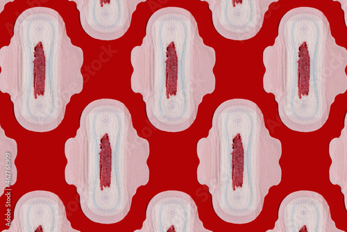Pattern of bloodstained sanitary pads against red background photo