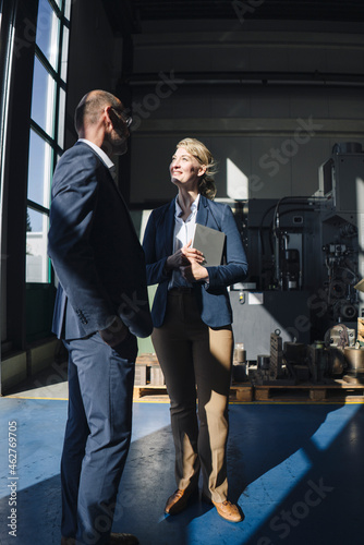 Businessman and smiling businesswoman talking in a factory photo